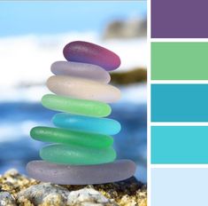 a stack of rocks sitting on top of a sandy beach next to the ocean with color swatches