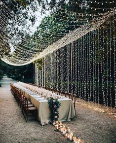 a long table is set up with candles and greenery for an outdoor wedding reception