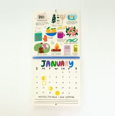 a calendar with stickers on it sitting on a white table next to a wall