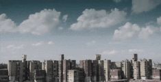 an aerial view of a city with tall buildings and clouds in the sky above it