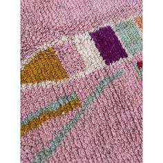 a close up view of a rug with different colors and patterns on it, including pink