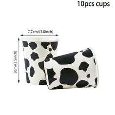 two cups with black and white spots on them, one has a cup in the shape of a cow