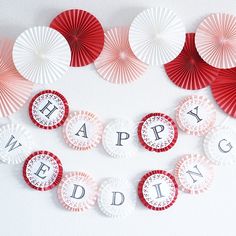 red and white paper fans with the words happy wedding spelled out on them are arranged in a heart shape