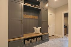 a large mud room with gray cabinets and baskets