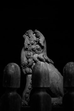 a lion statue sitting on top of a wooden table next to some fence posts in the dark