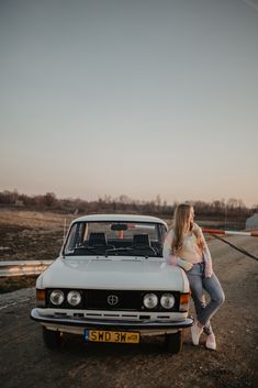 a woman sitting on the hood of a car