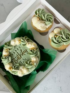 two cupcakes with green frosting in a box