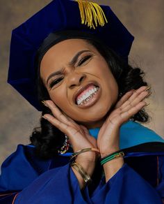 a woman wearing a graduation cap and gown with her hands on her chest, smiling