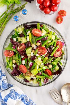 a salad in a glass bowl with tomatoes, lettuce and other vegetables