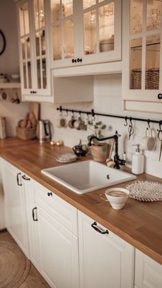 a kitchen with white cabinets and wooden counter tops, along with hanging utensils