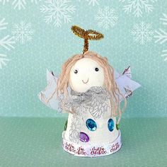 a little angel doll sitting on top of a green table next to snowflakes