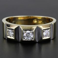 a yellow gold ring with three diamonds on it, sitting on a black surface in front of the camera