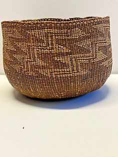 a brown woven bowl sitting on top of a white table