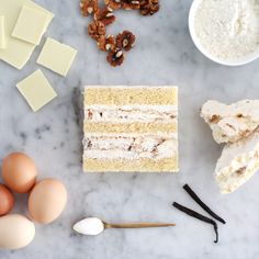 ingredients for cake laid out on a marble counter top, including eggs, butter, and walnuts