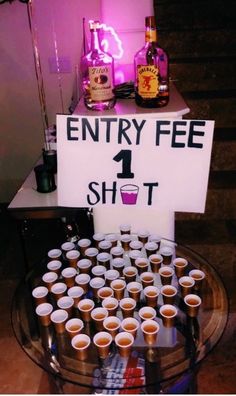 there is a sign that says entry fee 1 shot on the table with cups in front of it