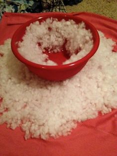 a red bowl filled with rice sitting on top of a table next to a pile of white rice