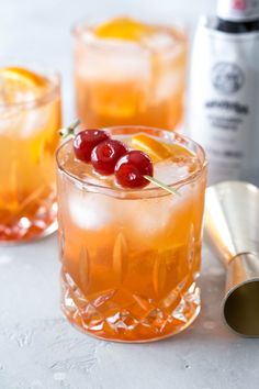 two glasses filled with drinks and garnished with cherries