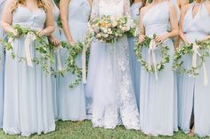 a group of women standing next to each other wearing blue dresses and holding bouquets