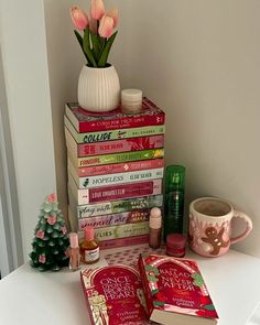 a stack of books sitting on top of a table next to a vase with flowers