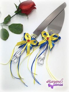 a knife and some flowers on a white surface with a red rose in the background