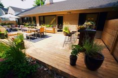 a deck with chairs, tables and plants on it