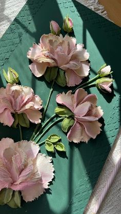 three pink flowers sitting on top of a green tray