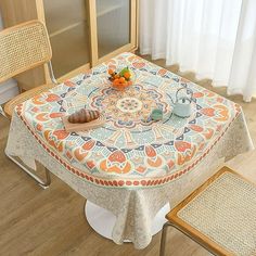 the table is covered with an intricately designed cloth and has a bowl of fruit on it