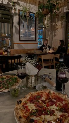 a table topped with two pizzas and glasses of wine