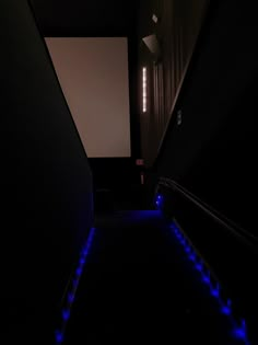 an empty room with blue lights on the floor and black walls, along with a projection screen