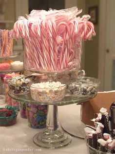 there are many candy canes in the glass bowl and on the table is an assortment of candies