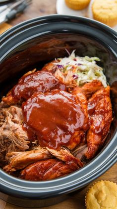 a slow cooker filled with meat, coleslaw and some muffins