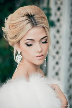 a woman in a white fur coat and earrings