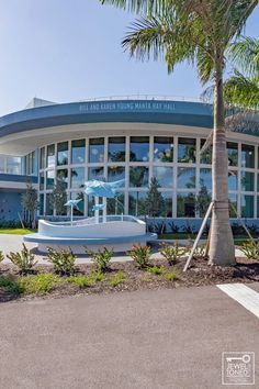 the front entrance to an office building with palm trees and blue sky in the background