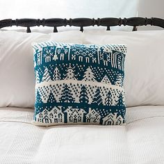 a white and blue pillow on top of a bed with pillows in front of it