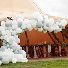 white balloons are hanging from the ceiling in front of a tent