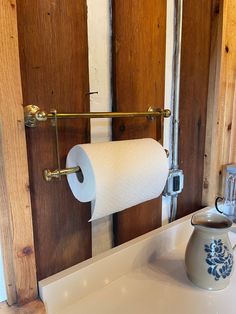 a roll of toilet paper sitting on top of a bathroom sink next to a wooden door