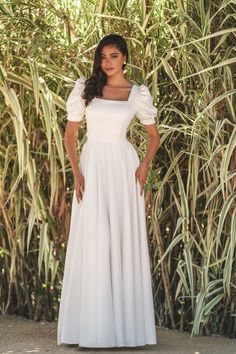 A wedding dress with a classic silhouette has a fitted bodice and flowy skirt with a square neckline and puff sleeves. Square Neck Wedding Dress, Simple Wedding Dress Boho, Wedding Dresses Lds, Sweetheart Bridal, Vintage Wedding Dress Boho, Minimal Wedding Dress, Modest Wedding Gowns, Pink Wedding Dresses, Modest Wedding