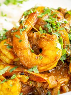 a close up of a plate of food with shrimp and rice on the side, garnished with cilantro