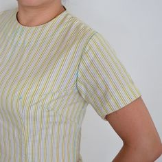 a woman with her hands on her hips posing for the camera while wearing a yellow and white striped shirt