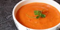 a white bowl filled with red soup and garnished with parsley on top