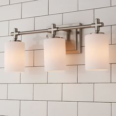 a bathroom light that is on the side of a wall with white bricks behind it