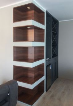 an empty room with wooden shelves on the wall and a black chair in front of it