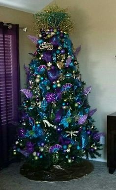 a blue christmas tree with purple and green decorations