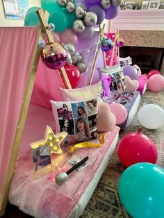 a bed with balloons, pictures and photos on it in front of a pink curtain