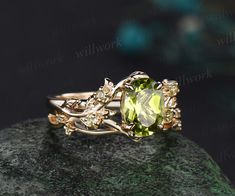 a gold ring with an oval cut green stone surrounded by small white diamonds on top of a rock