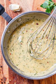 a pot filled with sauce and whisks on top of a wooden table