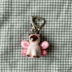 a keychain with a cat on it sitting on a checkered table cloth