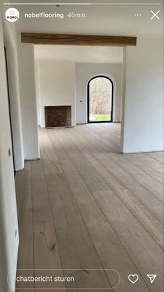 an empty room with wooden floors and white walls, looking into the open door to another room