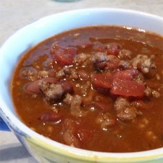 a bowl filled with meat and beans on top of a table