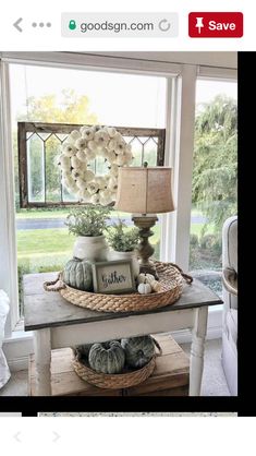 a table topped with baskets filled with white flowers and pumpkins next to a window